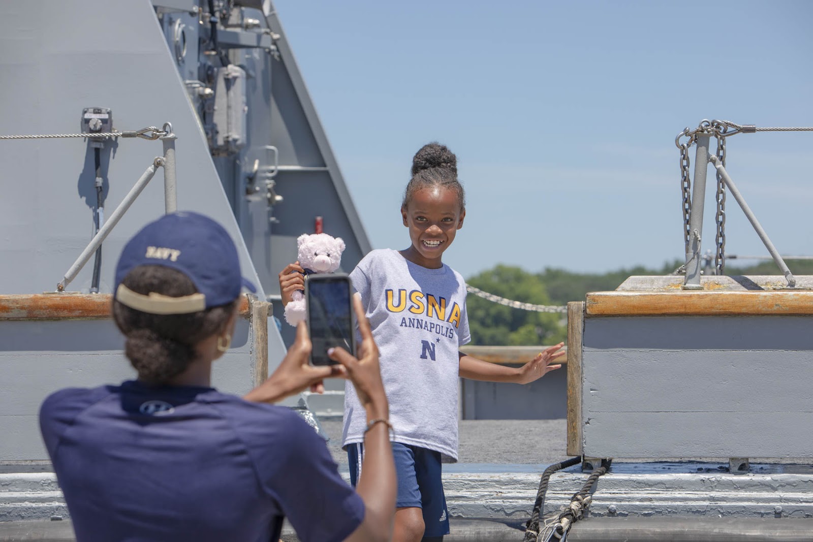 Midshipman takes a photo of a little girl. 